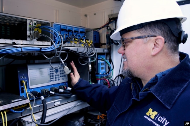 This photo from the University of Michigan shows tester Jim Lollar working inside a traffic control cabinet at the Mcity Test Facility. (Jeremy Little/University of Michigan College of Engineering via AP)