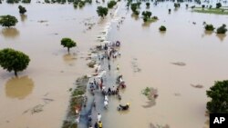 FILE - People walk through floodwaters after heavy rainfall in Hadeja, Nigeria, Sept 19, 2022.