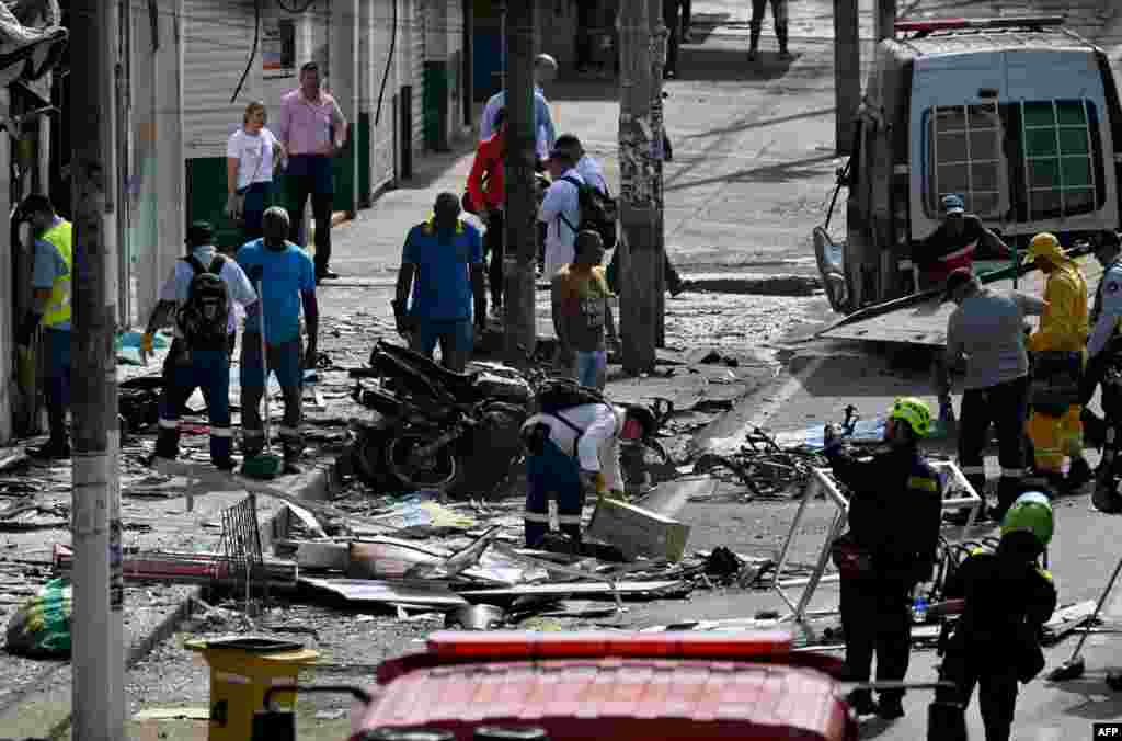 Police officers and civilians inspect the scene of the explosion in Jamundi, Valle del Cauca province, Colombia.&nbsp;The explosion left at least two police officers injured according to local authorities.