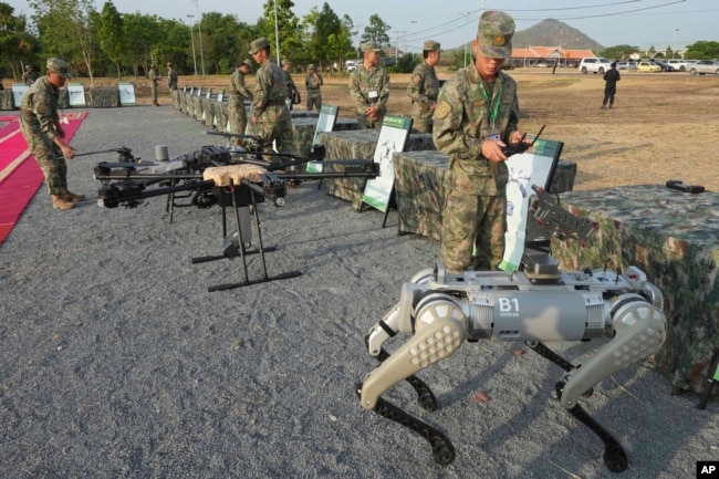 Seorang tentara China (kanan) menguji senjata yang dilengkapi robot sebelum latihan militer Naga Emas (Golden Dragon) di Desa Svay Chock, Provinsi Kampong Chhnang, di utara Phnom Penh, Kamboja, 16 Mei 2024. (Foto: Heng Sinith/AP Photo)