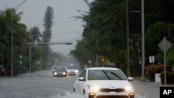 Mobil melintasi jalanan yang digenangi banjir di Surfside, Florida, pada 11 Juni 2024. (Foto: AP/Wilfredo Lee)