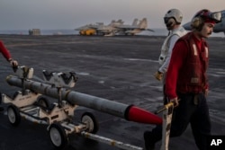 An ordnance man transports ammunition to a fighter jet on the flight deck of the USS Dwight D. Eisenhower in the Red Sea, June 11, 2024, preparing to load it.