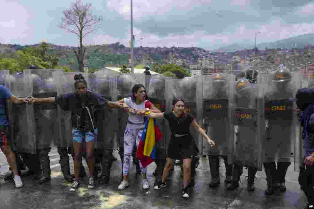 Residents try to block a street to protest the official results declaring President Nicolas Maduro&#39;s reelection, the day after the presidential election as National Guards work to remove them in Caracas, Venezuela.