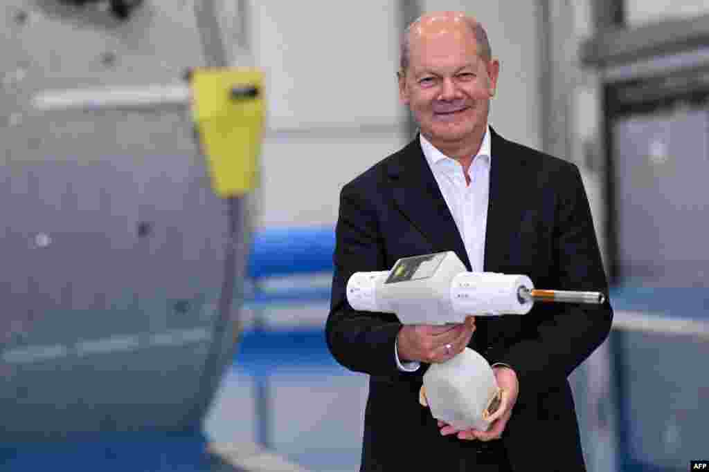 German Chancellor Olaf Scholz poses with a cordless electric screwdriver used during diving training at the Neutral Bouyancy Facility during a visit to ESA's European Astronaut Centre in Cologne, western Germany.