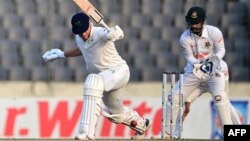 ঢাকার শের-ই-বাংলা জাতীয় ক্রিকেট স্টেডিয়ামে বাংলাদেশ ও আয়ারল্যান্ডের মধ্যে টেস্ট ক্রিকেট ম্যাচের দ্বিতীয় দিনে আয়ারল্যান্ডের পিটার মুরকে একটি শট খেলতে দেখছেন বাংলাদেশের উইকেটরক্ষক লিটন দাস। ৫ এপ্রিল, ২০২৩। মুনির উজ জামান/এএফপি