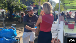 Una comerciante dona al voluntario Patrick Long varias barras de pan.