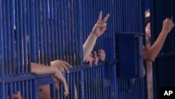 FILE - Detainees flash hand gestures at an immigration detention center in Bangkok, Thailand, Jan. 21, 2019.