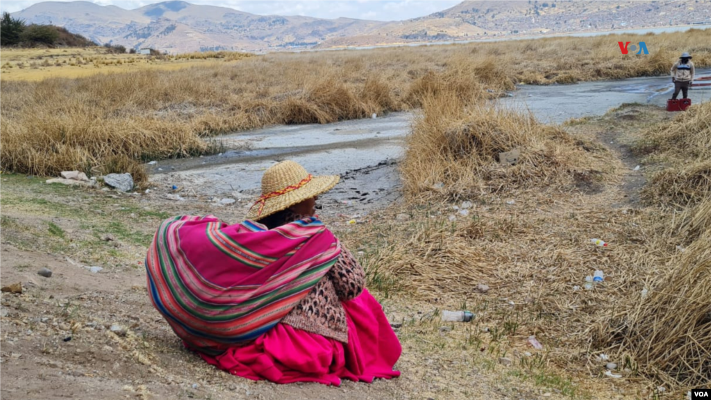 La comerciante aymara Carmen Quispe, de 56 años, observa el canal cada vez más seco a la espera de embarcar hacia la isla flotante de los Uros donde vive.