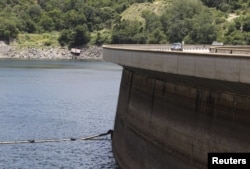 FILE - A motorist drives on top of the Kariba Dam wall in Kariba, Zimbabwe, Feb. 19, 2016.