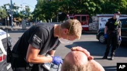 Seorang petugas paramedis dari tim ambulans Falck Northwest menangani seorang pria yang tampak kepayahan karena gelombang panas yang menyerang wilayah Salem, Oregon, pada 26 Juni 2021. (Foto: AP/Nathan Howard)