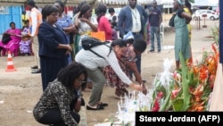 Parents et amis déposent des bougies et des fleurs en mémoire des disparus du naufrage d'un ferry dans le port de Libreville, le 13 mars 2023. 