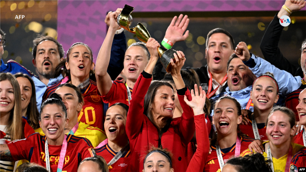 La reina Letizia de España levanta el trofeo, mientras las jugadoras y los oficiales de España celebran después de ganar el partido de fútbol final de la Copa Mundial Femenina de Australia y Nueva Zelanda 2023.