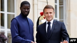 FILE - Senegal's President Bassirou Diomaye Faye (L) shakes hands with France's President Emmanuel Macron as they meet at the Elysee Presidential Palace in Paris, June 20, 2024.