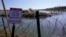 Migrants cross the Rio Grande into the US from Mexico behind concertina wire and a sign warning that it's dangerous and illegal to cross, Jan. 3, 2024, in Eagle Pass, Texas. 