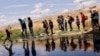 Migrantes que buscan asilo cruzan el Río Bravo para regresar a México desde Estados Unidos, luego de que miembros de la Guardia Nacional de Texas extendieran alambre de púas para impedir que cruzaran, visto desde Ciudad Juárez, México, el 13 de mayo de 2023.