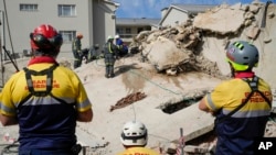 FILE - Rescue workers search the site of a building collapse in George, South Africa, May 8, 2024. Rescue teams are searching for dozens of construction workers missing after a multi-story apartment complex collapsed.