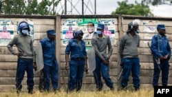 FILE - Police line up in front of a ZANU-PF campaign poster to block Citizens Coalition for Change from holding a rally in Marondera, March 12 2022. Authorities charged 39 opposition activists with political violence on June 12, 2023, for allegedly attacking a ZANU-PF office.