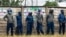 FILE - Police line up in front of a ZANU-PF campaign poster to block Citizens Coalition for Change from holding a rally in Marondera, March 12 2022. Authorities charged 39 opposition activists with political violence on June 12, 2023, for allegedly attacking a ZANU-PF office.