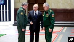 Presidenti Putin duke biseduar me shefin e shtabit Gjeneral Valery Gerasimov (majtas) dhe ministrin e mbrojtjes Sergei Shoigu (djathtas)