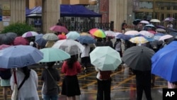 资料照片：家长和老师们冒雨在北京一所学校外等候正在参加一年一度的全国高考的考生们。(2024年6月7日)