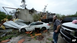 Orang-orang berdiri di luar gedung E.C.O. Builders, pasca badai hebat yang melanda wilayah di Slidell, Louisiana, Rabu, 10 April 2024. (AP/Gerald Herbert)