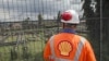 FILE - An employee at the Shell Agbada 2 flow station looks at the station from behind a gate in Port Harcourt, Sept. 30, 2015. Oil companies like Shell have often blamed theft and sabotage for oil spills, a claim contested by environmental groups. 