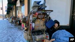 Tim Varner, 57, uses blankets to stay warm in the snow as he huddles with his belongings in a storefront in Portland, Oregon, Feb. 24, 2023.