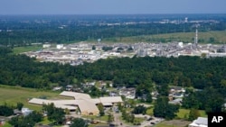 A school and neighborhoods sit near the Denka Performance Elastomer Plant, back, in Reserve, La., Sept. 23, 2022. The plant emits chloroprene, listed as a carcinogen in California and a likely one by the Environmental Protection Agency.