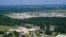 A school and neighborhoods sit near the Denka Performance Elastomer Plant, back, in Reserve, La., Sept. 23, 2022. The plant emits chloroprene, listed as a carcinogen in California and a likely one by the Environmental Protection Agency.