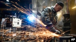 A volunteer welds a heating stove from old car rims in workshop in Siauliai, some 230 kilometers northwest of Vilnius, Lithuania, Feb. 2, 2023. 