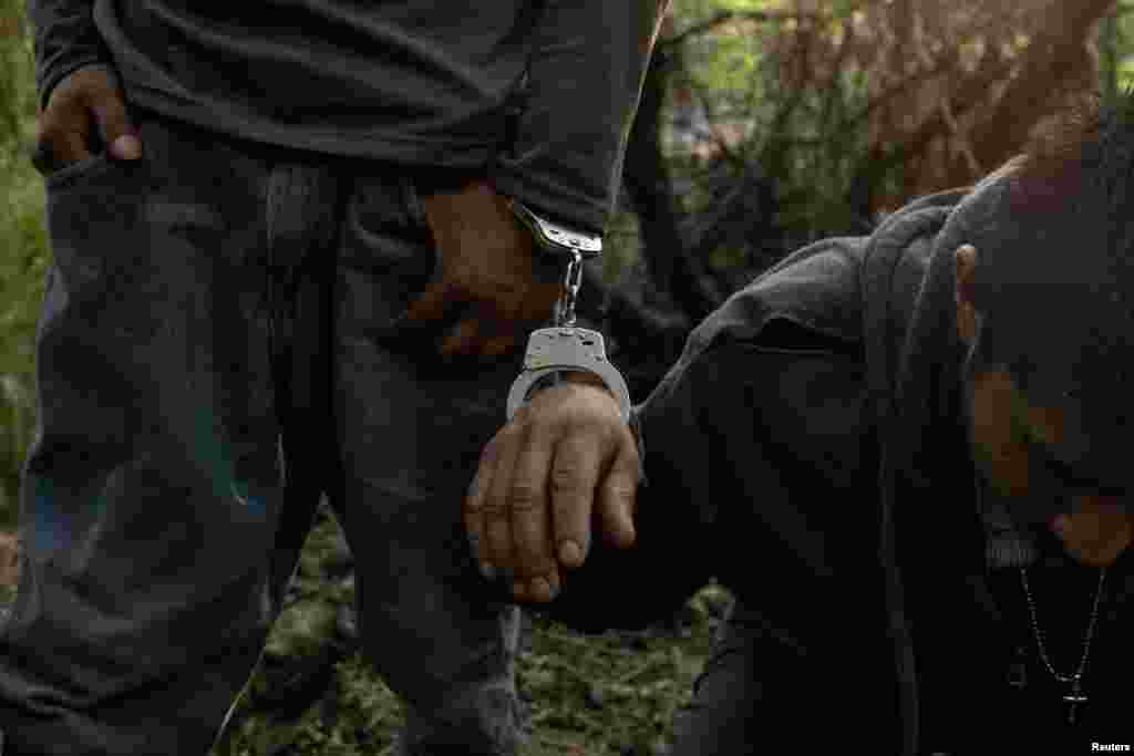 A migrant man from Guatemala sits handcuffed and exhausted as he is detained along with others for hiding in thick brush after crossing into the United States from Mexico in Havana, Texas, June 11, 2024. 