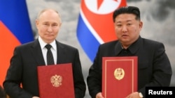 Рускиот претседател Владимир Путин и севернокорејскиот лидер Ким Џонг Ун се фотографираат за време на церемонијата на потпишување договор по билатералните разговори во Пјонгјанг, Северна Кореја, 19 јуни 2024 година.