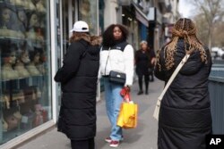 Perempuan berjalan melewati salon tata rambut di Paris, Kamis, 28 Maret 2024.(AP/Aurelien Morissard)