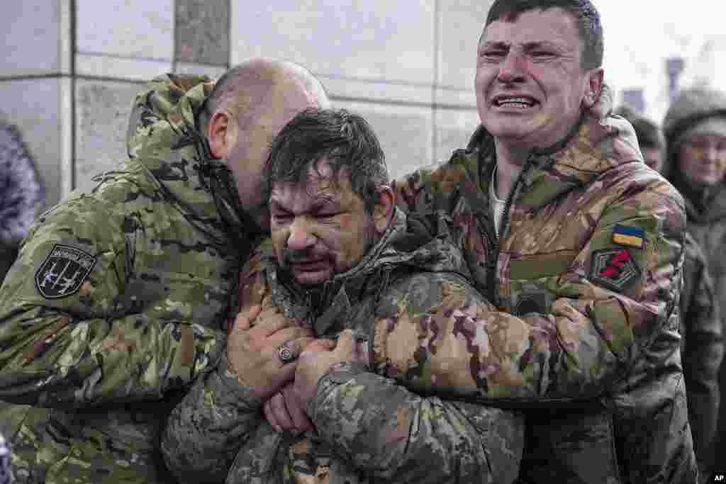 Ukrainian servicemen cry near the coffin of their comrade Andrii Trachuk during his funeral service on Independence square in Kyiv, Ukraine.