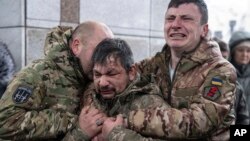 Ukrainian servicemen cry near the coffin of their comrade Andrii Trachuk during his funeral service on Independence square in Kyiv, Ukraine. (AP Photo/Evgeniy Maloletka)