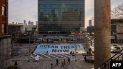FILE: Activists from Greenpeace display a banner outside U.N. headquarters during negotiations there on a treaty to protect the high seas, in New York. Taken Feb. 27, 2023.