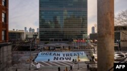 Activists from Greenpeace display a banner outside U.N. headquarters during negotiations there on a treaty to protect the high seas, in New York, Feb. 27, 2023.