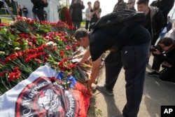 A fighter of the Wagner Group private military force places a sledgehammer, one of the symbols of Wagner, at an informal memorial next to Wagner headquarters in St. Petersburg, Russia, on Aug. 24, 2023.