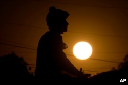 A rider is silhouetted against the rising sun after taking a horse for a workout at Churchill Downs May 5, 2023, in Louisville, Ky.