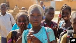 FILE- Balkissa Barro, 10, center, walks to school with friends in the Burkina Faso village of Dori, Burkina Faso, Oct. 20, 2020.