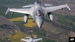 Un avión de combate militar F-16 de la Fuerza Aérea portuguesa y un avión de combate militar F-16 de la Fuerza Aérea Rumana que participan en la Misión de Vigilancia Aérea del Báltico de la OTAN operan en el espacio aéreo lituano el lunes 22 de mayo de 2023. 