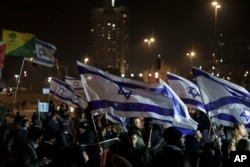 Holding up Israeli flags people take part in a protest against humanitarian aid entering Gaza and against the hostages exchange deal with Hamas, in Jerusalem, Jan. 25, 2024.