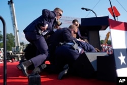 Republican presidential candidate former President Donald Trump is covered by U.S. Secret Service agents at a campaign rally, July 13, 2024, in Butler, Pennsylvania.