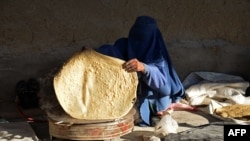 FILE - A burqa-clad Afghan woman prepares bread at a workplace to sell at a market in Kandahar, Afghanistan, Jan. 5, 2023.
