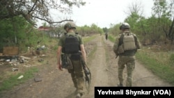Ukrainian soldiers walk through the combat zone in Storozheve, Ukraine, June 23, 2023.