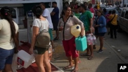 In the aftermath of Hurricane Otis, people wait in line with containers to buy gasoline in Acapulco, Mexico, Oct. 28, 2023.