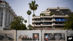 Seorang warga tampak berjalan di depan sejumlah poster bintang perfilman di Croisette menjelang Festival Film Cannes di Cannes, Prancis, pada 12 Mei 2024. (Foto: AP/Daniel Cole)