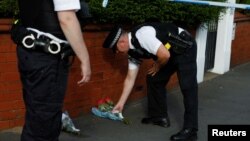 Seorang polisi meletakkan bunga di balik garis polisi dekat tempat kejadian perkara penikaman di Southport, Inggris, Senin, 29 Juli 2024. (Foto: Temilade Adelaja/Reuters)