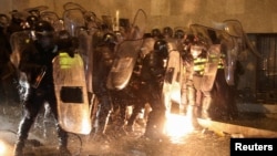 Police officers attempt to extinguish a fire as protesters throw Molotov cocktails during a rally against the "foreign agents" law in Tbilisi, Georgia, March 7, 2023.
