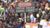 A man holds a sign reading: 'Down with France down with ECOWAS' as supporters of Niger's National Council for Safeguard of the Homeland gather at the General Seyni Kountche stadium in Niamey, Aug. 26, 2023. 